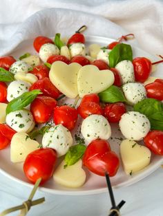 a plate filled with mozzarella and cherry tomatoes on skewers next to utensils