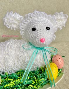 a crocheted lamb with an easter egg in it's mouth on a plate