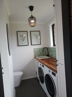 a washer and dryer in a bathroom with pictures on the wall above it