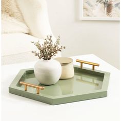 a white table with a green tray on it and a vase filled with flowers in the middle