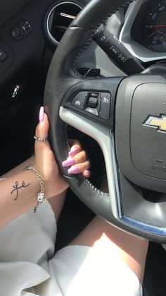 a woman with pink nail polish driving a car