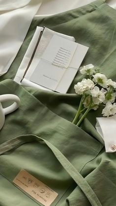 some flowers are laying on a bed next to an open book and a cup of coffee