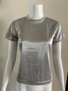 For your consideration Vintage Liz Claiborne metallic silver top. Embossed USA logo. Poly nylon Lycra spandex blend. Made in USA. Marked PETITE SMALL Fits like a modern women's XS/S Pre owned, shows general wear. Overall great shirt. Does show minor snags and surface wear throughout. The bottom hem has a small area where the stitch is missing, but it still wears fine. Please review photos to best determine condition and message with any questions. Zoom for details. Shown on size small mannequin Siliver Shiny Shirt, Babydoll Tee, Silver Shirt, Small Mannequin, 90s Party, Silver Top, Silver Tops, Liz Claiborne, Emboss