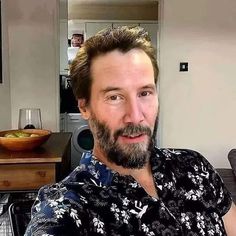 a man with a goatee is sitting in front of a kitchen counter and looking at the camera