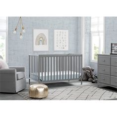 a baby's room with a crib, dresser and chair in grey tones