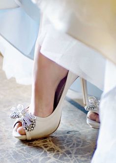 the bride's shoes are adorned with pearls and bows on her wedding day, while she is waiting for her groom to walk down the aisle