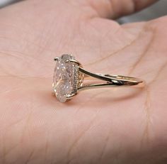 a close up of a person's hand holding a ring with a diamond on it