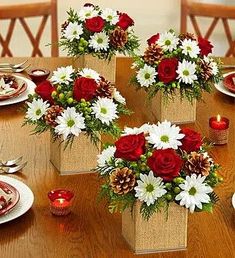 four vases filled with red and white flowers on top of a wooden dining table