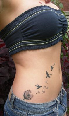 a woman's stomach with dandelions and birds on the side, tattoo