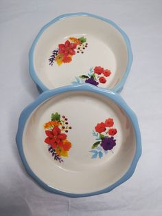 two blue and white plates with flowers painted on them are sitting side by side in front of each other