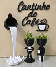 two black and white vases with plants in them next to a sign that reads cantuno do cafe