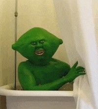 a green man sitting in a bathtub with his hands on the side of it