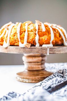 a bundt cake with icing sitting on top of a wooden stand