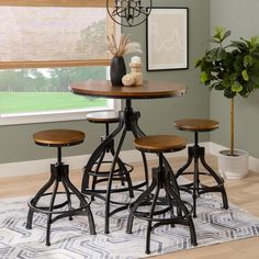 a kitchen table with four stools and a potted plant in the corner next to it