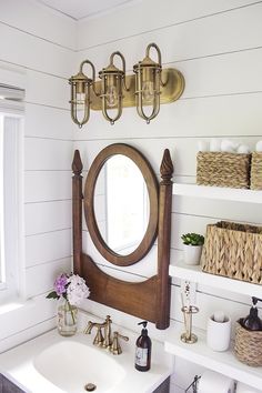 a bathroom with white walls and wood accents on the wall, along with a round mirror