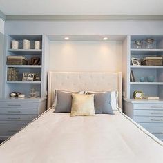 a white bed sitting in the middle of a bedroom next to blue cabinets and drawers