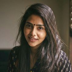 a woman with long dark hair smiling at the camera while wearing a black and white shirt