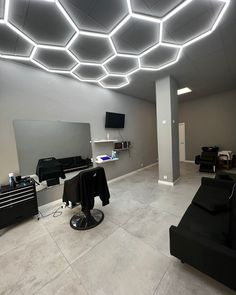 a room that has some black furniture and lights on the ceiling, with white walls