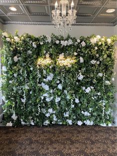 an artificial flower wall with the word love spelled in gold lettering on it and surrounded by white flowers