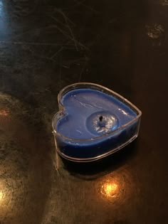 a heart shaped container sitting on top of a table next to a candle holder with a blue lid