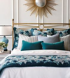 a bed with blue and white comforters, pillows and lamps on the nightstands