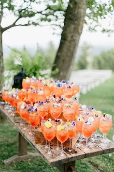 there are many glasses on the table with orange drinks in them and one is empty