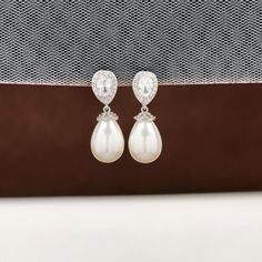 These delicate drop pearl bridal earrings, a perfect harmony of crystal and pearl that brings a sophisticated yet affordable elegance to your wedding day. These silver wedding earrings are a testament to understated luxury, suitable for the bride, bridesmaids, and the mother of the bride. ✨ Highlights: 💖 Subtle Sparkle: The earrings feature a crystal-studded zirconia teardrop at the top, paired with a pristine white drop pearl at the bottom, creating a look that is both elegant and understated. Classic Pearl Chandelier Earrings For Wedding, Elegant Silver Pearl Earrings For Bride, Pearl White Crystal Drop Earrings For Wedding, Classic Pearl Drop Crystal Earrings For Wedding, Elegant Pearl Drop Earrings For Bride, Pearl White Drop Pearl Earrings For Wedding, Teardrop Pearl Bridal Earrings For Mother Of The Bride, Wedding Teardrop Dangle Earrings With Pearl Charm, Classic Pearl Drop Earrings For Mother Of The Bride