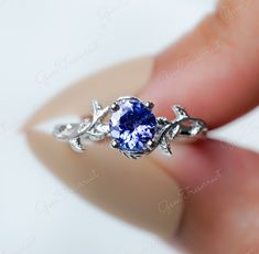 a close up of a person holding a ring with a blue stone in the center