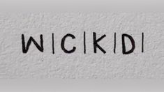 the word wickd is written in black ink on a white wall