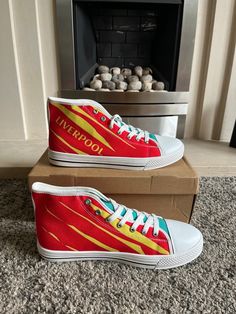 a pair of red and yellow shoes sitting on top of a box in front of a fireplace