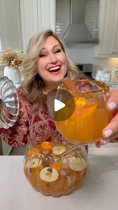 a woman holding up a glass filled with liquid and sliced bananas on top of it