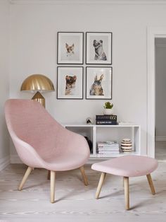 a pink chair and footstool in a white room with pictures on the wall