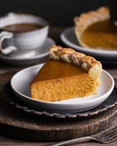 a slice of pumpkin pie on a plate with a cup of coffee in the background