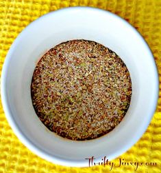 a white bowl filled with lots of different types of spices on top of a yellow table cloth