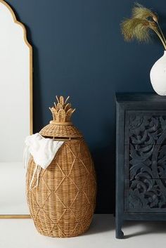 a white vase sitting on top of a wooden table next to a black cabinet and mirror