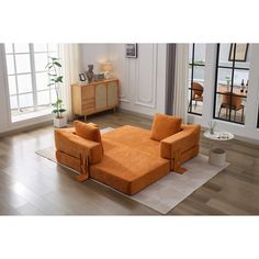 an orange couch sitting on top of a hard wood floor next to a white rug