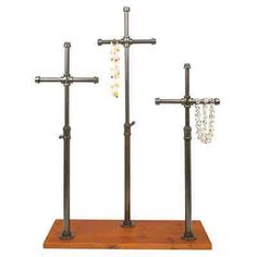 three metal crosses on wooden stand with beads hanging from the cross and beaded chain