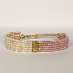 a close up of a bracelet on a white surface with a yellow and pink bead