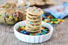 a stack of cookies with sprinkles in a white bowl on a wooden table