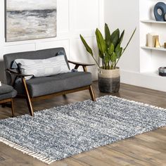 a living room with a rug, chair and potted plant