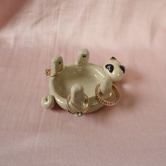 a small ceramic bear sitting on top of a pink cloth covered tablecloth with a gold chain around it's neck