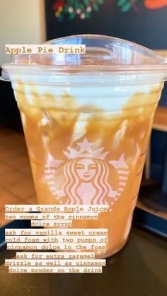 an apple pie drink in a plastic cup sitting on a table with the caption above it