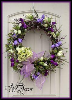 a wreath with purple and white flowers on the front door