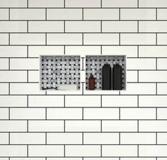 two windows in a white brick wall with black and grey tiles on the bottom floor