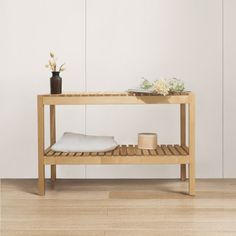 a wooden table with a white pillow and some vases on the shelf next to it