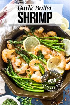 garlic butter shrimp and asparagus in a cast iron skillet with lemon wedges