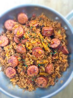 a bowl filled with rice and sausage on top of a wooden table