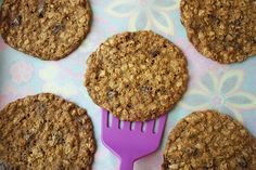 six oatmeal cookies and a purple fork on a blue tablecloth with flowers