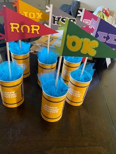 cups with blue pom - poms are sitting on a table in front of colorful signs