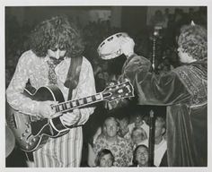 black and white photograph of two men playing guitars in front of an audience at a concert